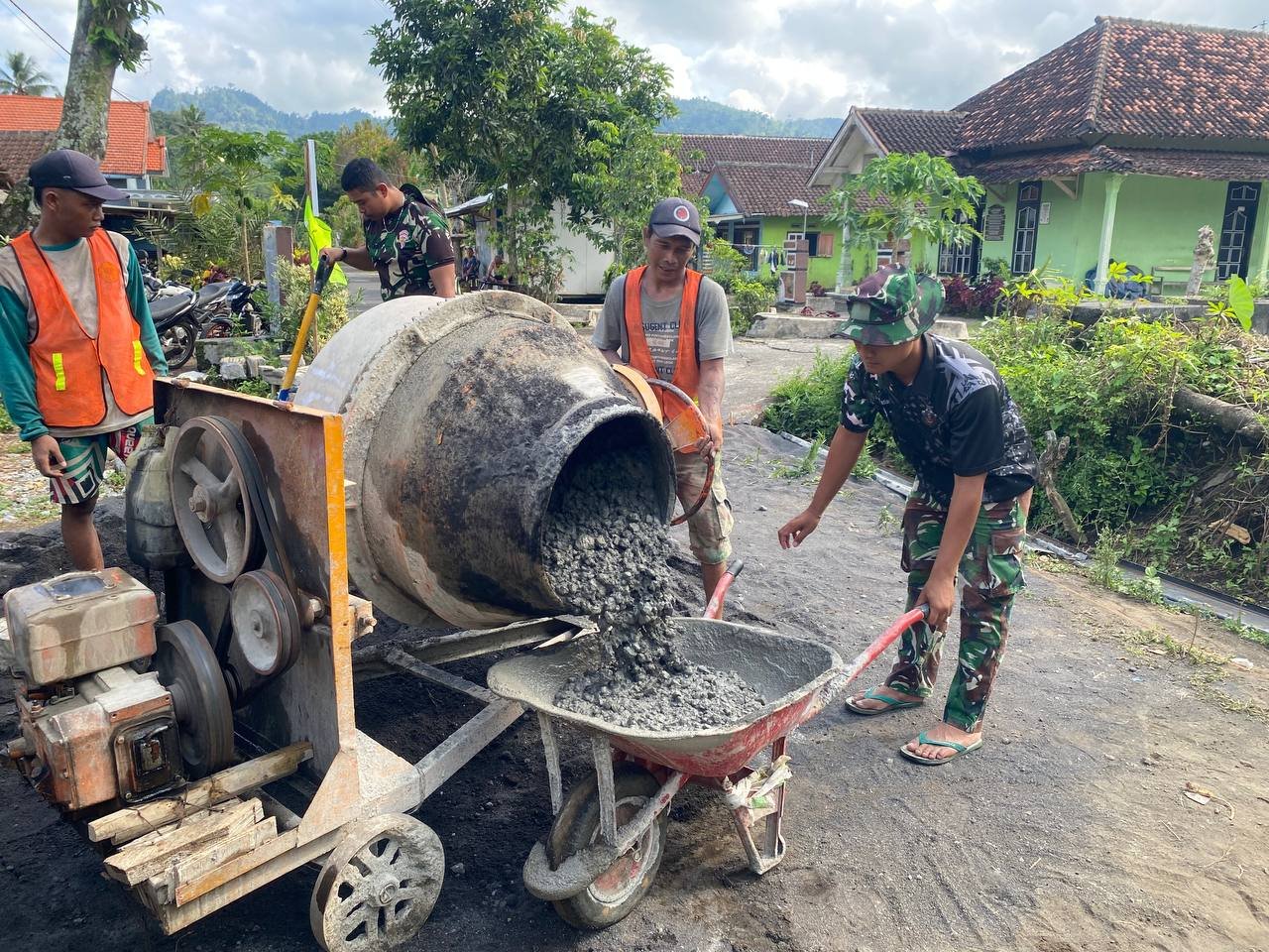 Anggota Satuan Tugas (Satgas) TMMD dari Yonzipur 5/Abw bersama warga Dusun Krajan 1A, Desa Lebakharjo, Kecamatan Ampelgading, bahu-membahu melanjutkan pekerjaan pengecoran jalan rabat beton