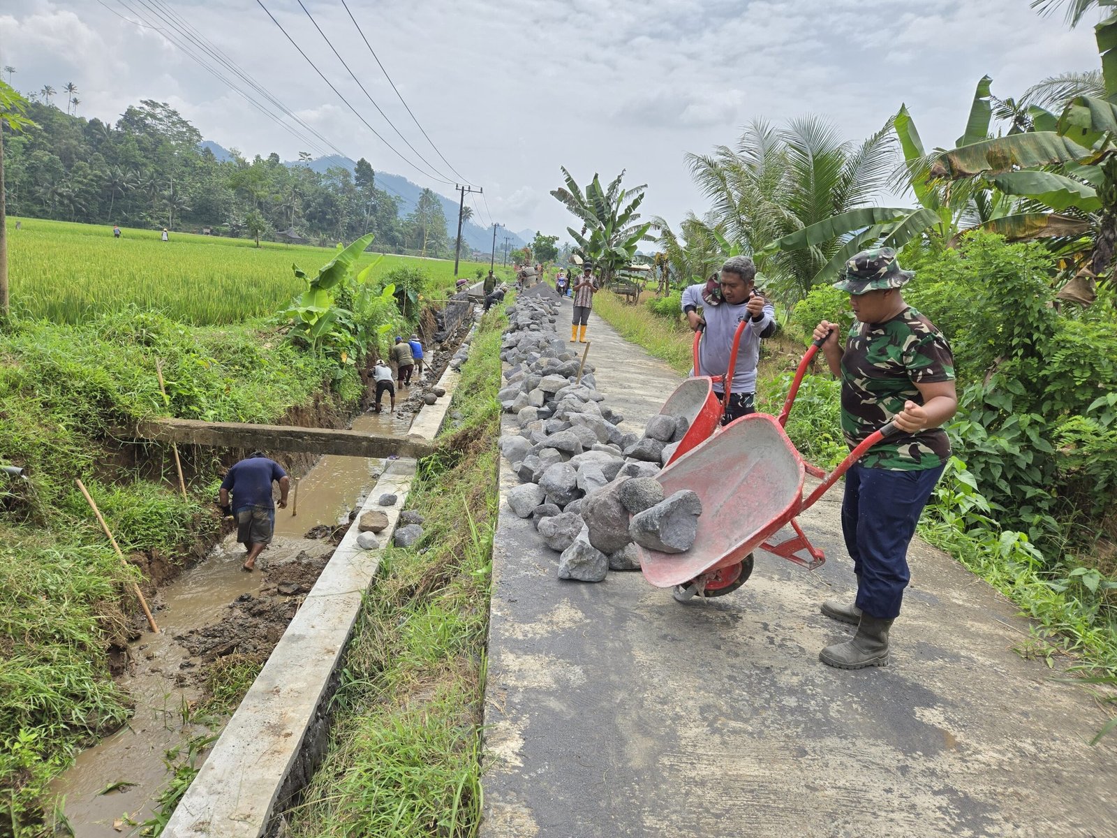 Di bawah teriknya matahari, personel Satuan Angkatan Laut (TNI AL) bersama Kodim 0818/Malang-Batu dan masyarakat setempat bahu-membahu melanjutkan pekerjaan saluran irigasi dalam program TMMD ke-126.